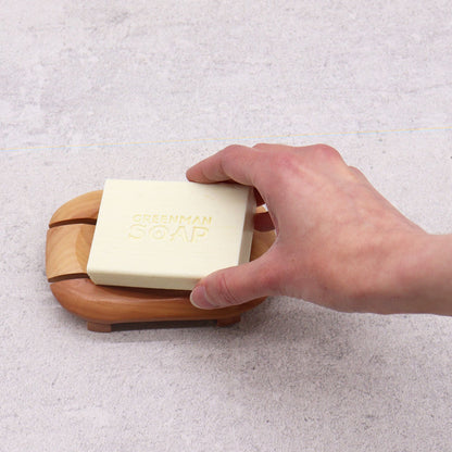 Alt Tag: Naseberry Wood Soap Dish – Oval in Rectangle with bar soap on oval-in-rectangle wooden tray, hand placing soap