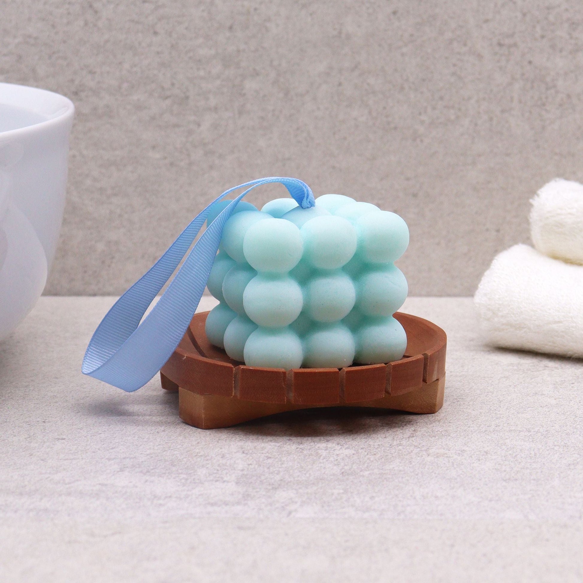 Naseberry Wood Soap Dish – Round 10x2 CM with drainage slots holding blue bubble soap bar in bathroom setting
