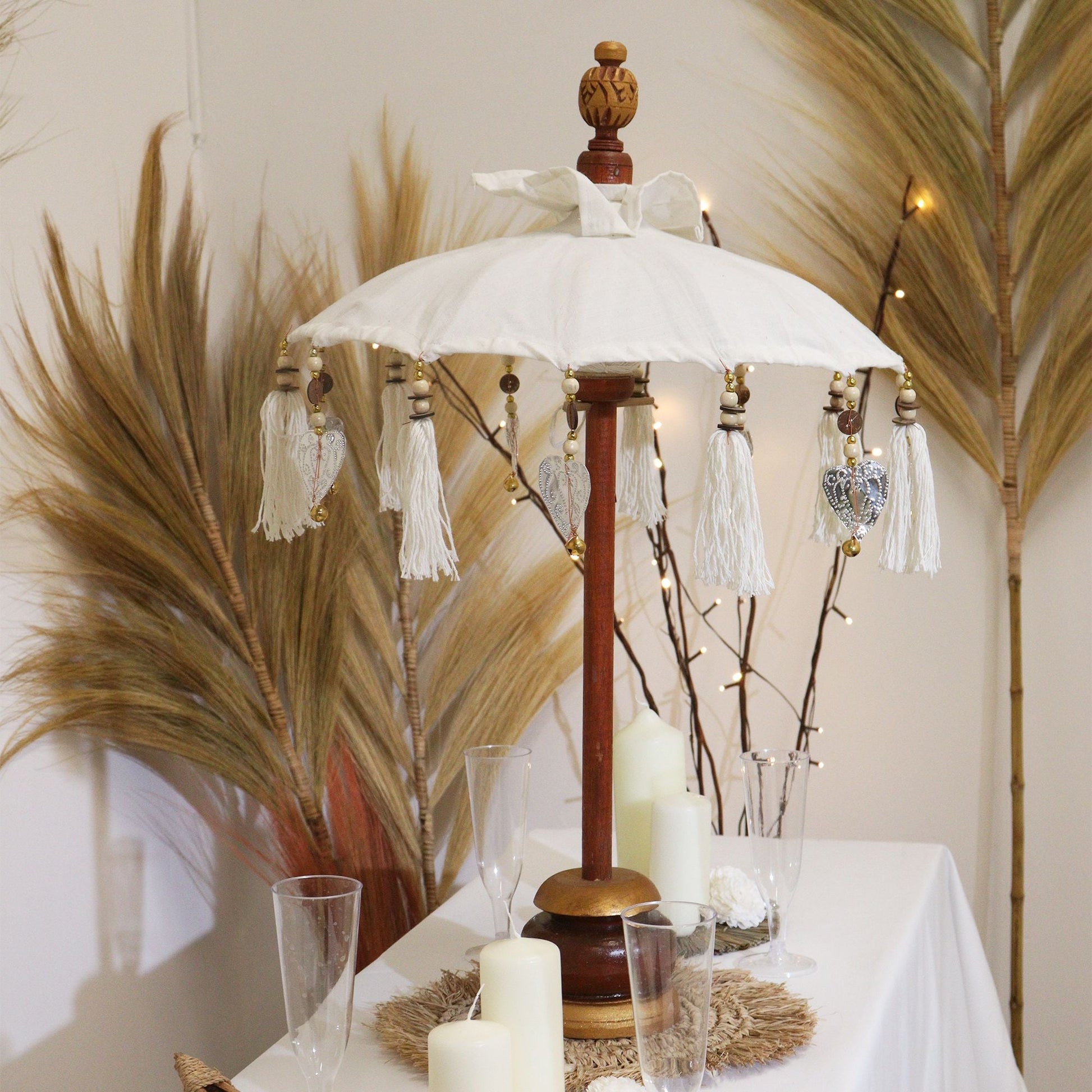 Alt Tag: Natural Canvas Bali Parasol – 40 CM de lona natural con poste de madera, borlas decorativas, sobre mesa de decoración