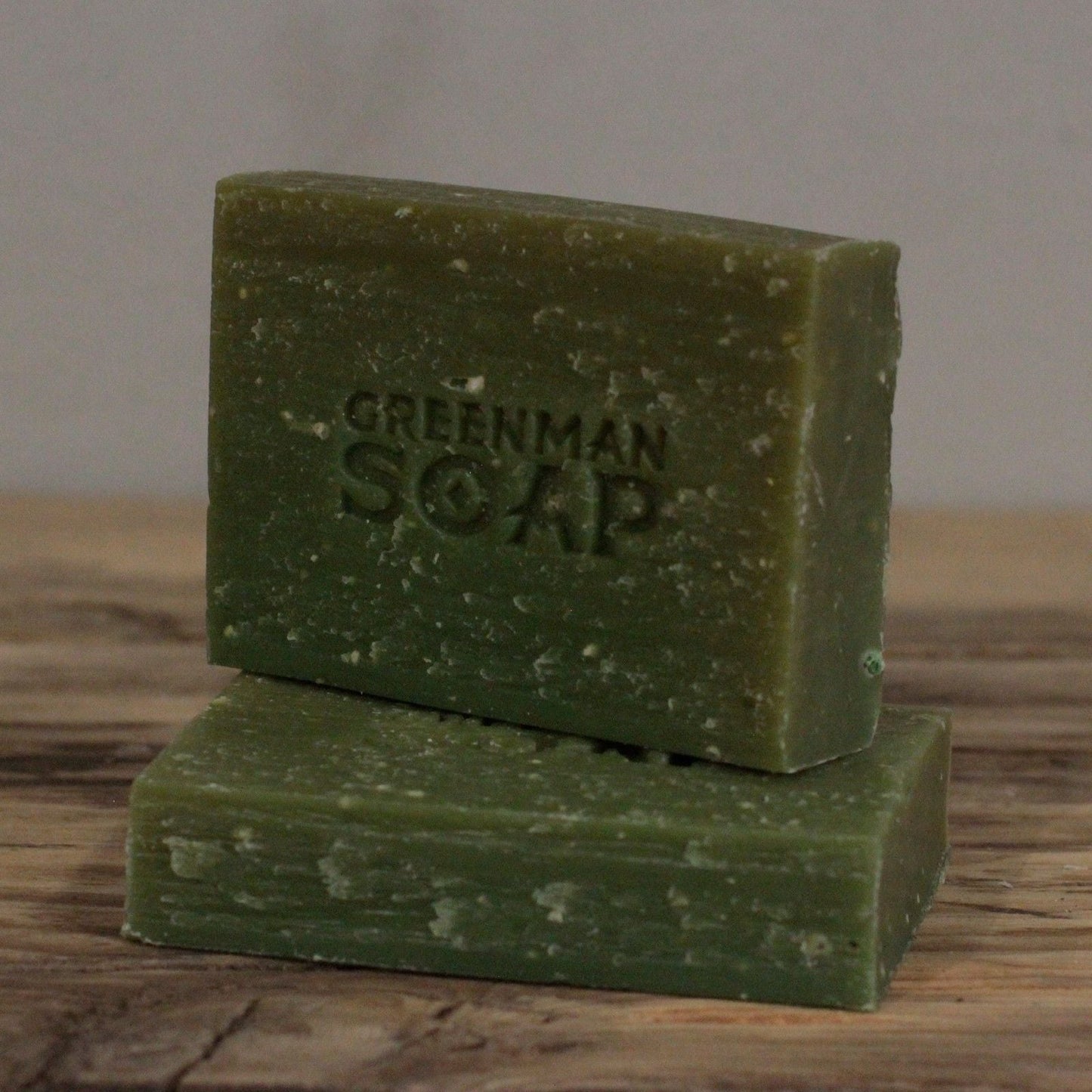 Alt Tag: Natural Gardener’s Scrub Soap – 100G Lemon & Basil green scrub soap bar stacked, Greenman Soap logo on rustic wooden surface