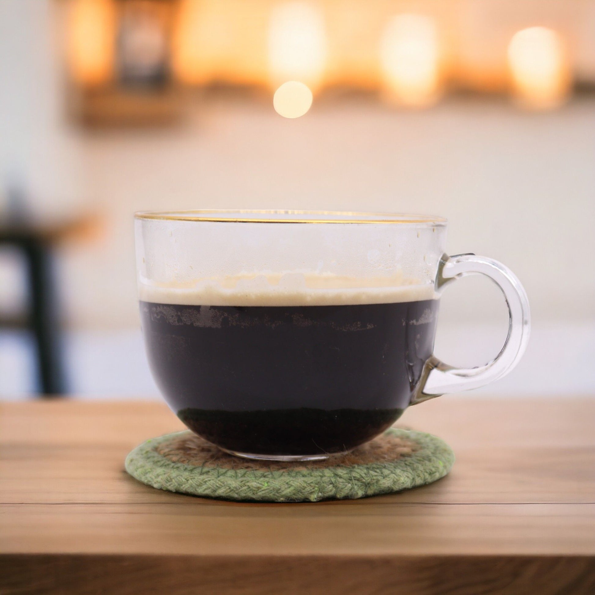 Posavasos naturales de yute y algodón – Set de 6 de 10CM con taza de café de vidrio sobre posavasos verde hecho a mano en mesa de madera