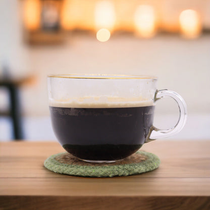 Posavasos naturales de yute y algodón – Set de 6 de 10CM con taza de café de vidrio sobre posavasos verde hecho a mano en mesa de madera