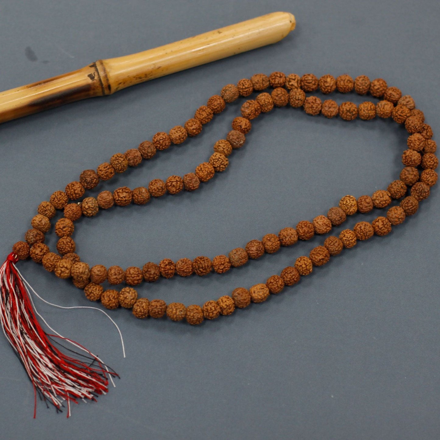 Alt Tag: Natural Wood Beads Rudraksha Mala – 7x2 CM, collar de cuentas de madera natural con borla roja, sobre fondo gris