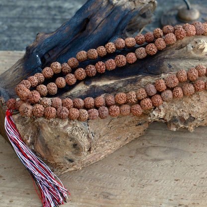 Alt Tag: Natural Wood Beads Rudraksha Mala – 7x2 CM, collar de cuentas rudraksha de madera natural con borla roja y blanca sobre madera