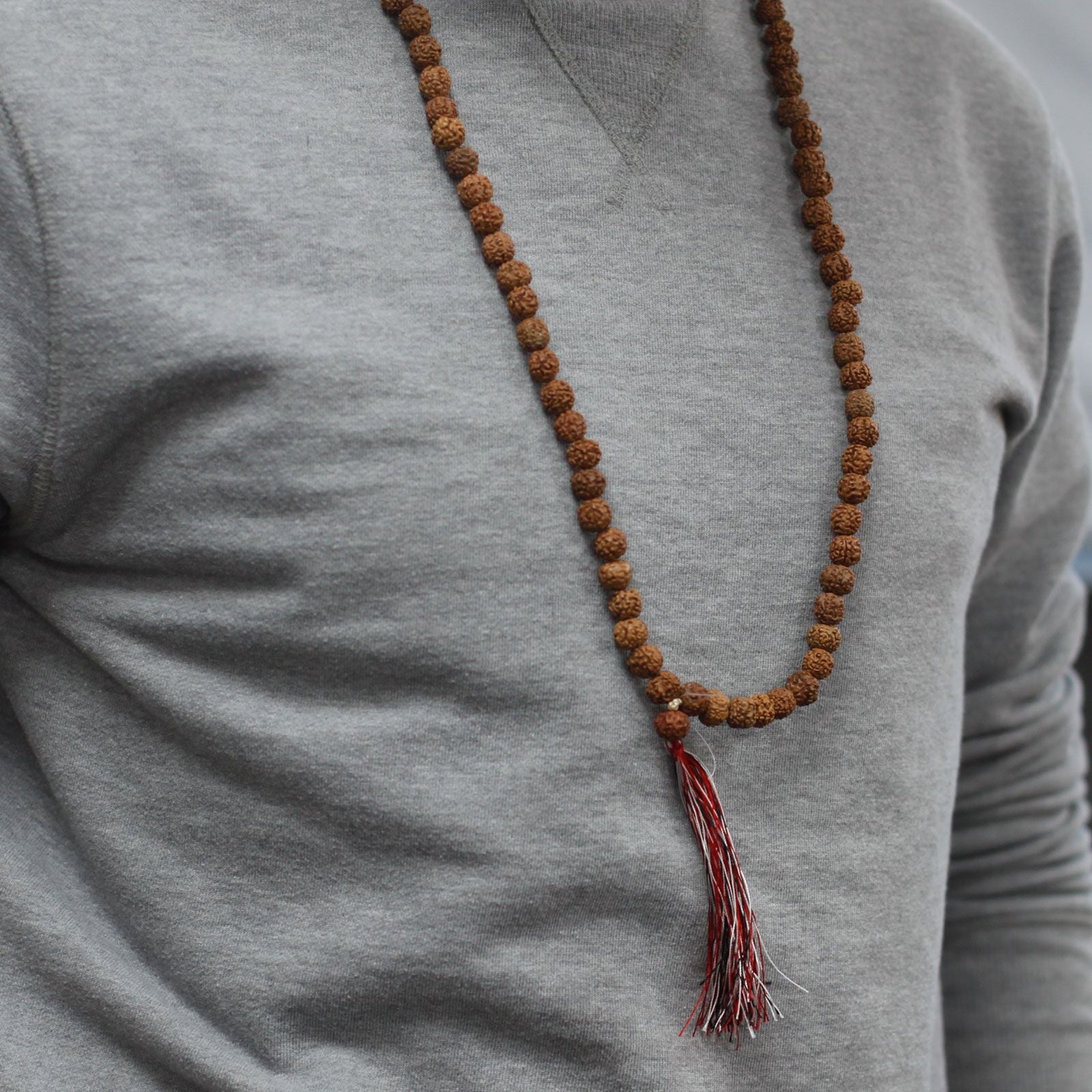 Alt Tag: Natural Wood Beads Rudraksha Mala – 7x2 CM necklace worn on grey shirt with brown beads and red tassel