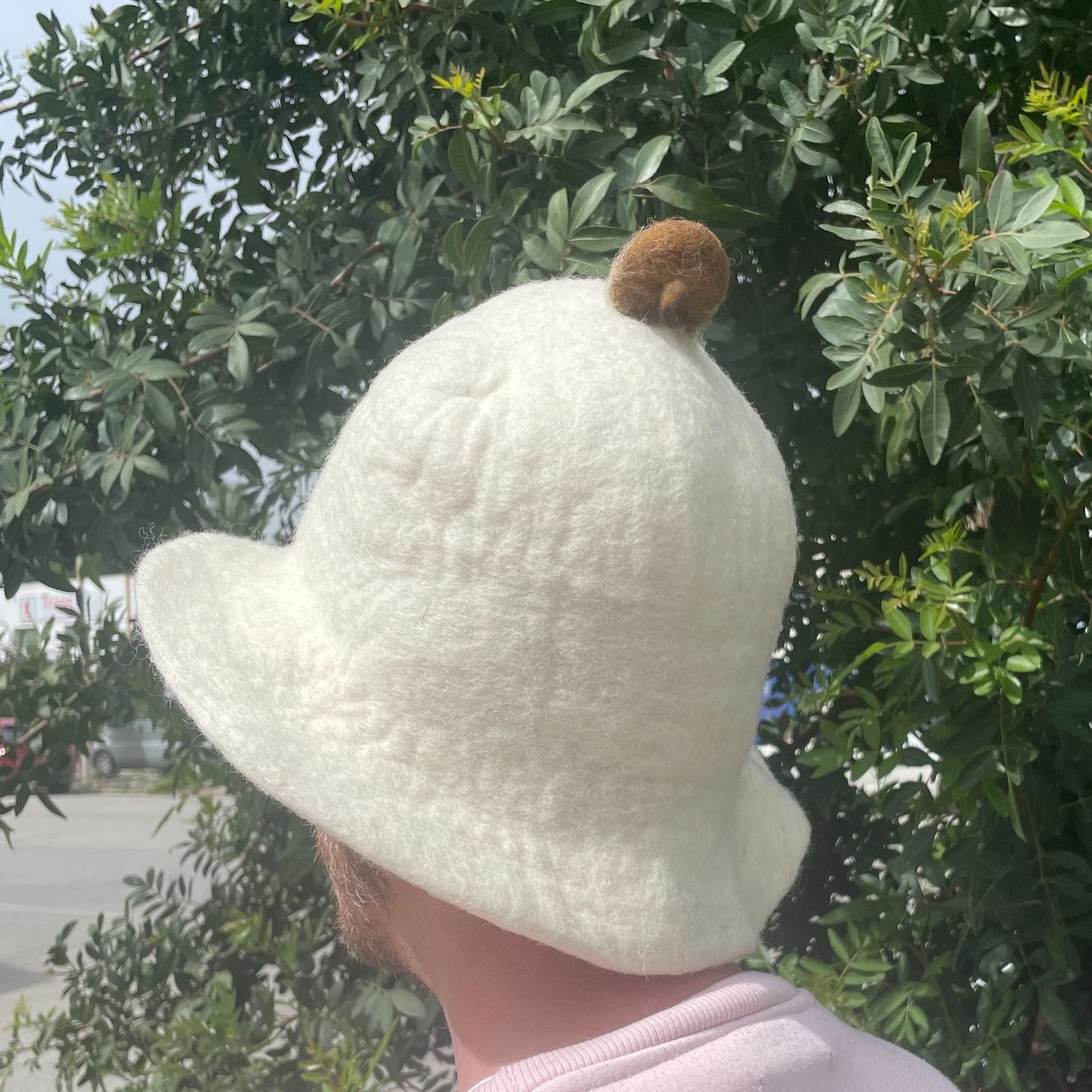 Natural Wool Felt Sauna Hat – 27x34 CM white wool felt sauna hat with pom pom, side view worn outdoors