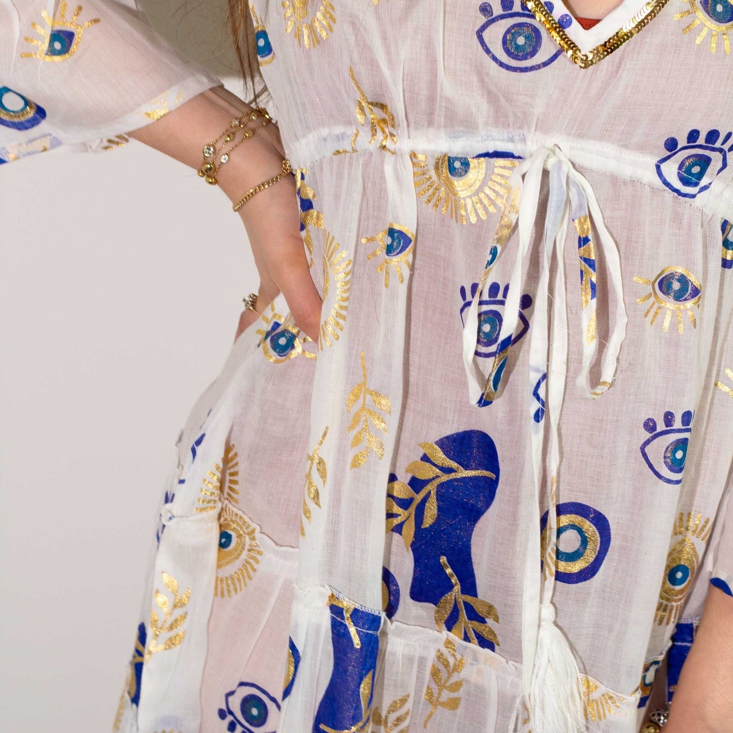 Nomad Sari Dress – White, Blue & Gold Evil Eye Design (LXL) close-up of white fabric with blue and gold evil eye motifs and waist tie