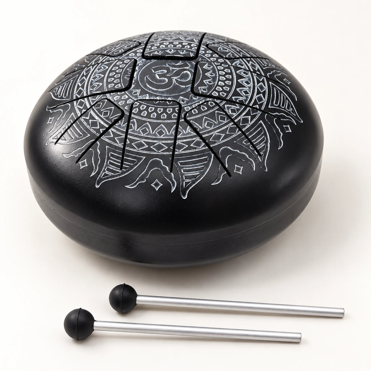 Oblique view of the black Om tongue drum showing its domed top, visible shell seam and two mallets resting in front.
