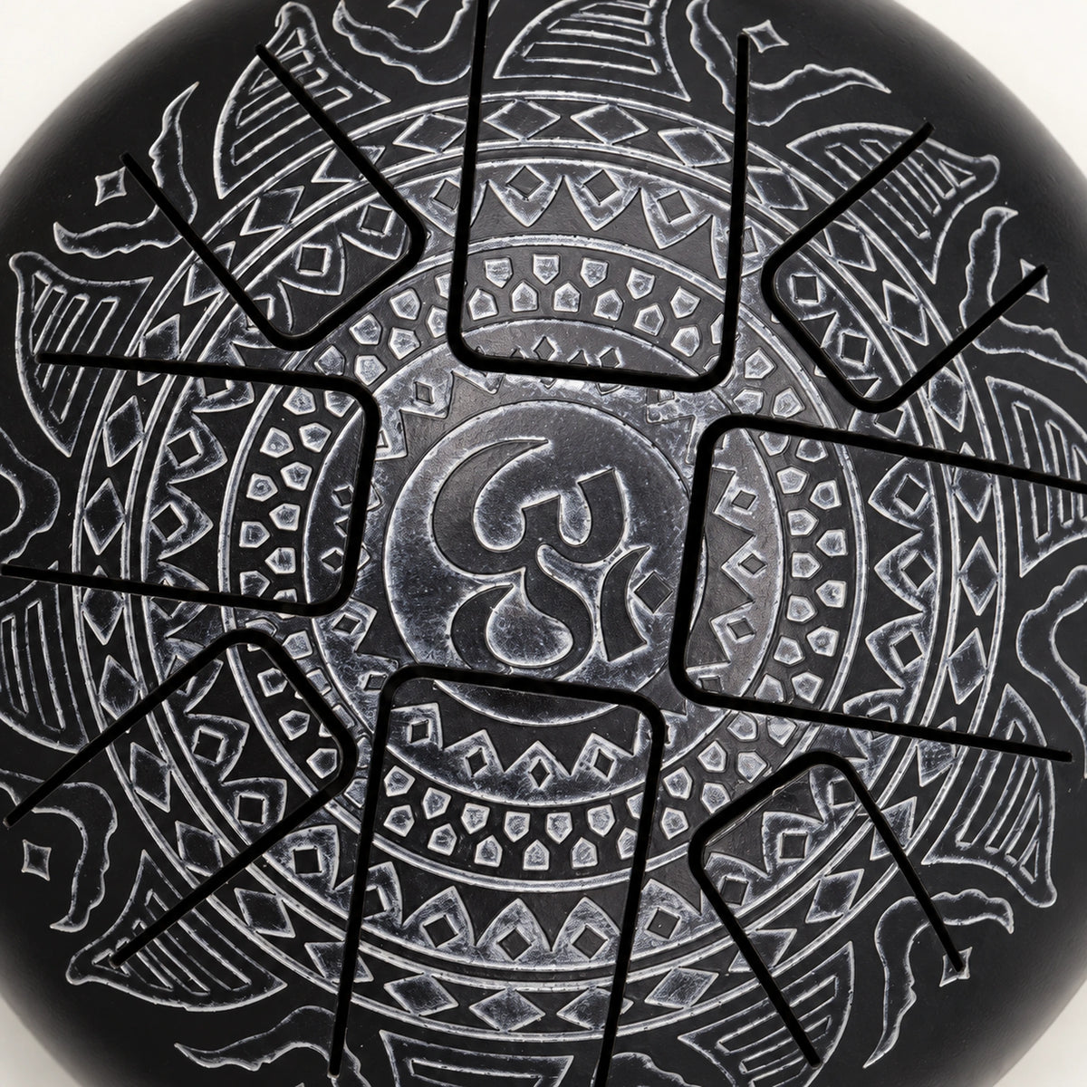 Close view of the silver-grey Om symbol and surrounding geometric engraving on the black drum surface.