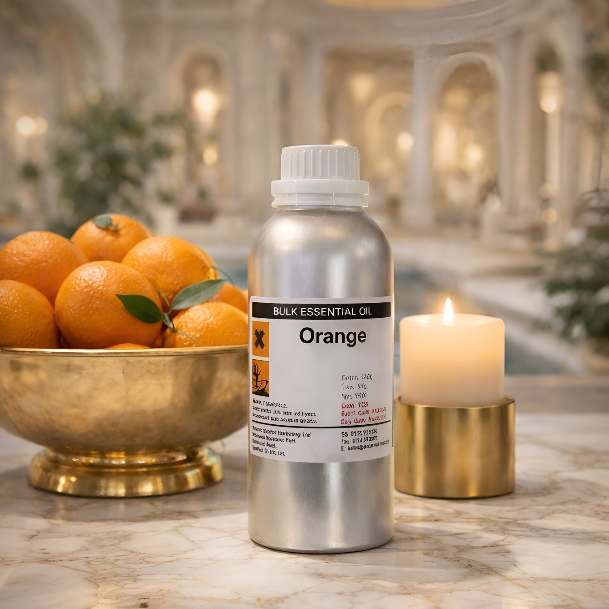 Ätherisches Orangenöl – 500G Großflasche auf einem Marmortisch neben einer Schale mit frischen Orangen und einer brennenden Kerze