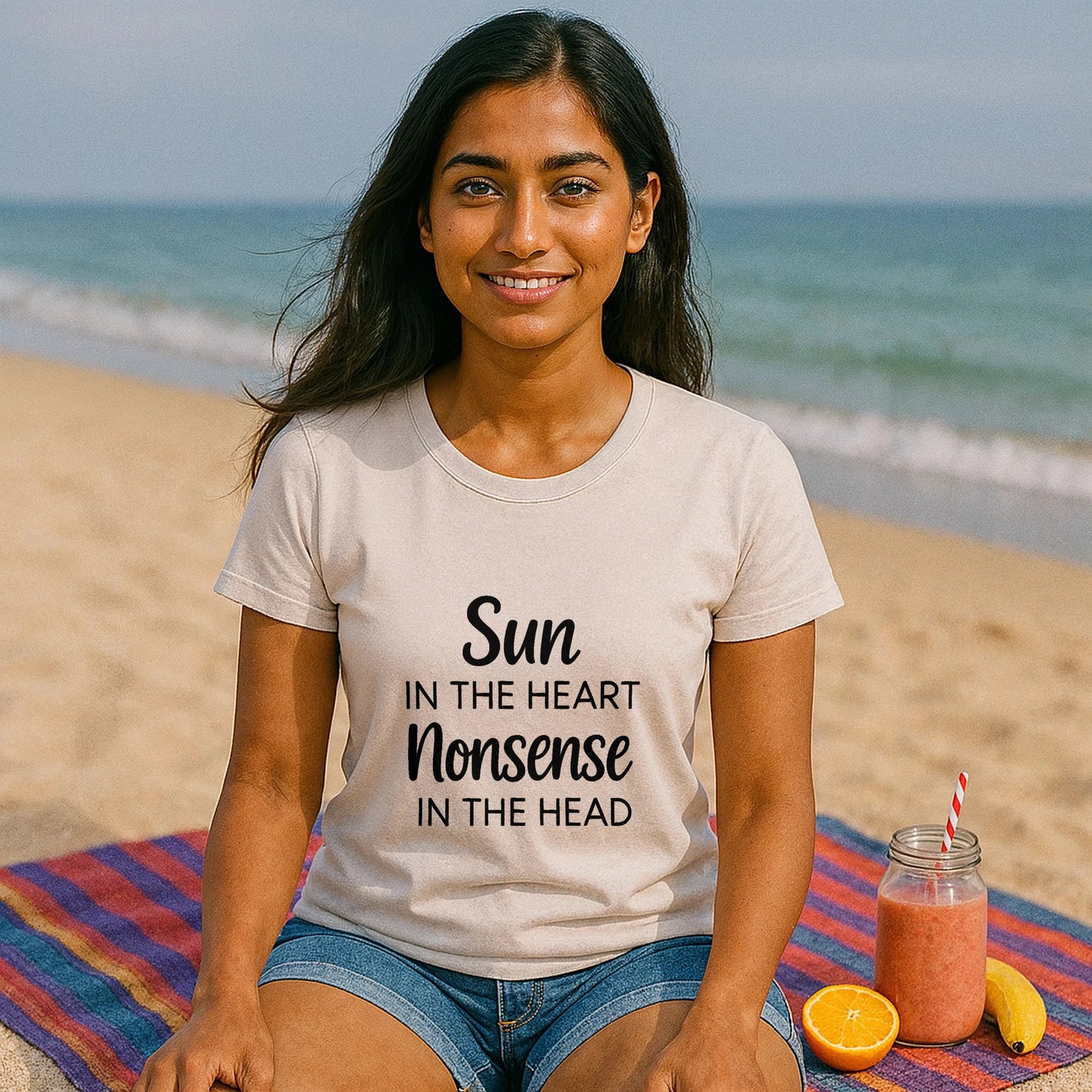 Alt Tag: Organic Tee Sun in the Heart Nonsense in the Head graphic organic cotton t-shirt worn by woman sitting on beach