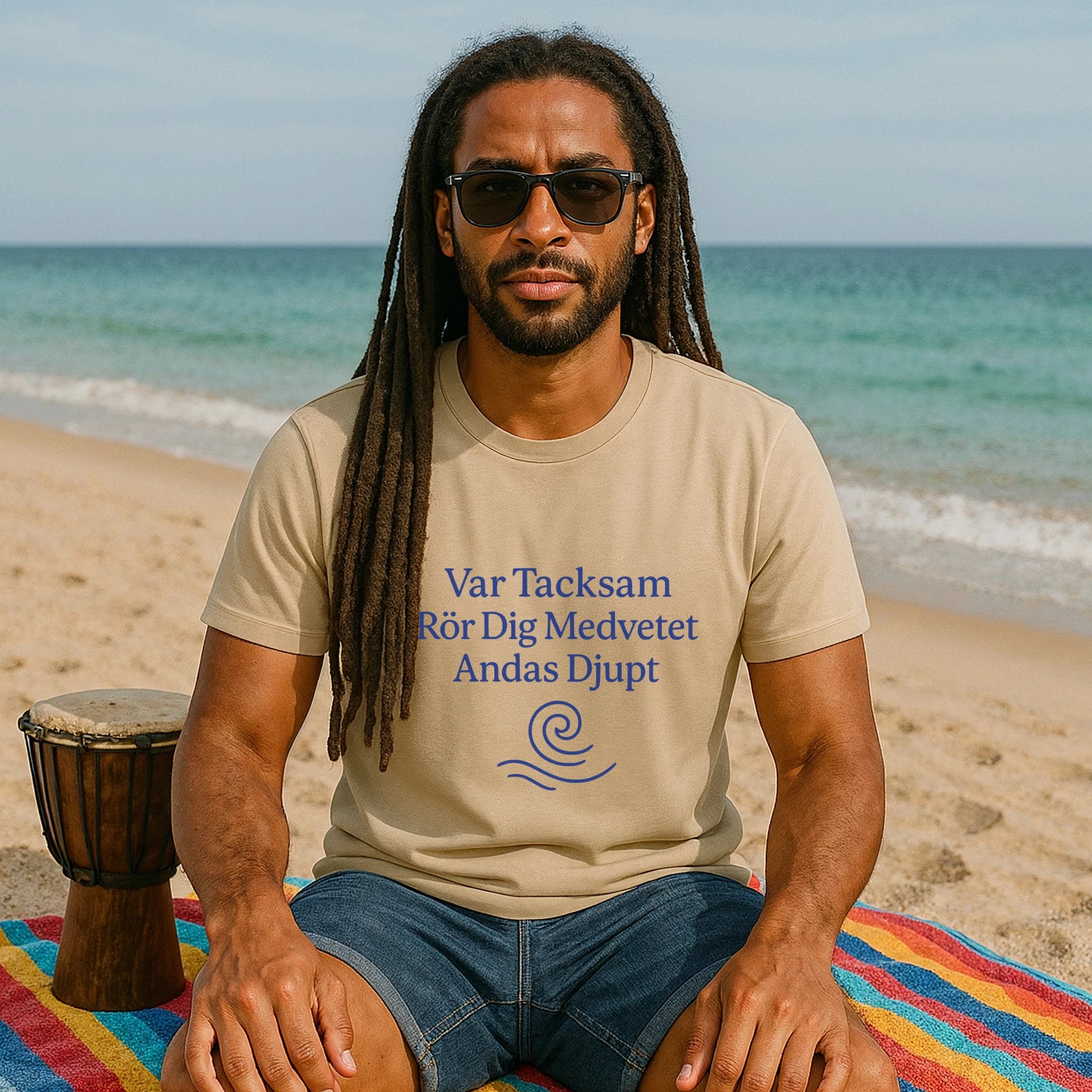 Yoga 100% Organic Cotton T-Shirt on model sitting on beach, beige tee with blue text print and sunglasses