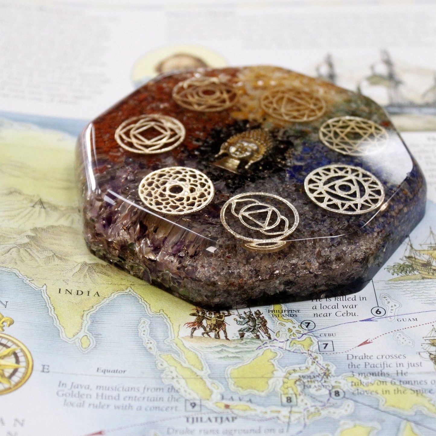 Alt Tag: Orgonite Desk Power Pack – Buddha Chakra – Large orgonite paperweight with chakra symbols, resin, metal and crystals on a desk map