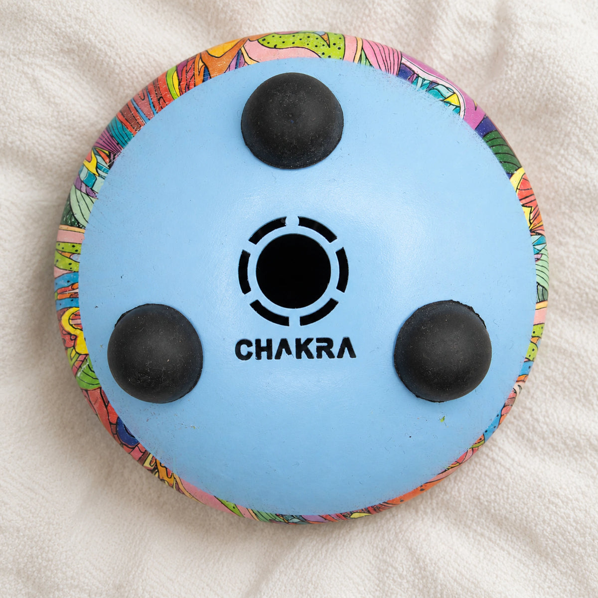 Pale blue underside of the Happy Drum with three black feet, a central opening and CHAKRA lettering.