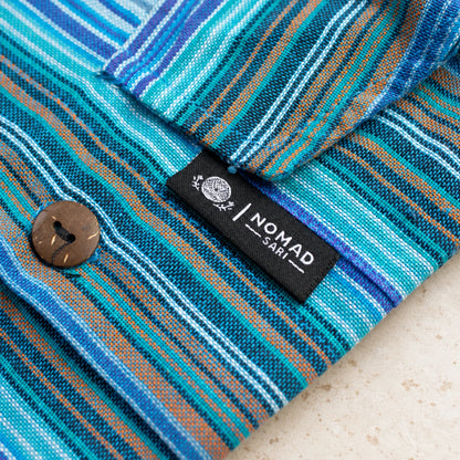Detail of the striped pocket flap with its brown button, visible stitching and black Nomad Sari brand tab.