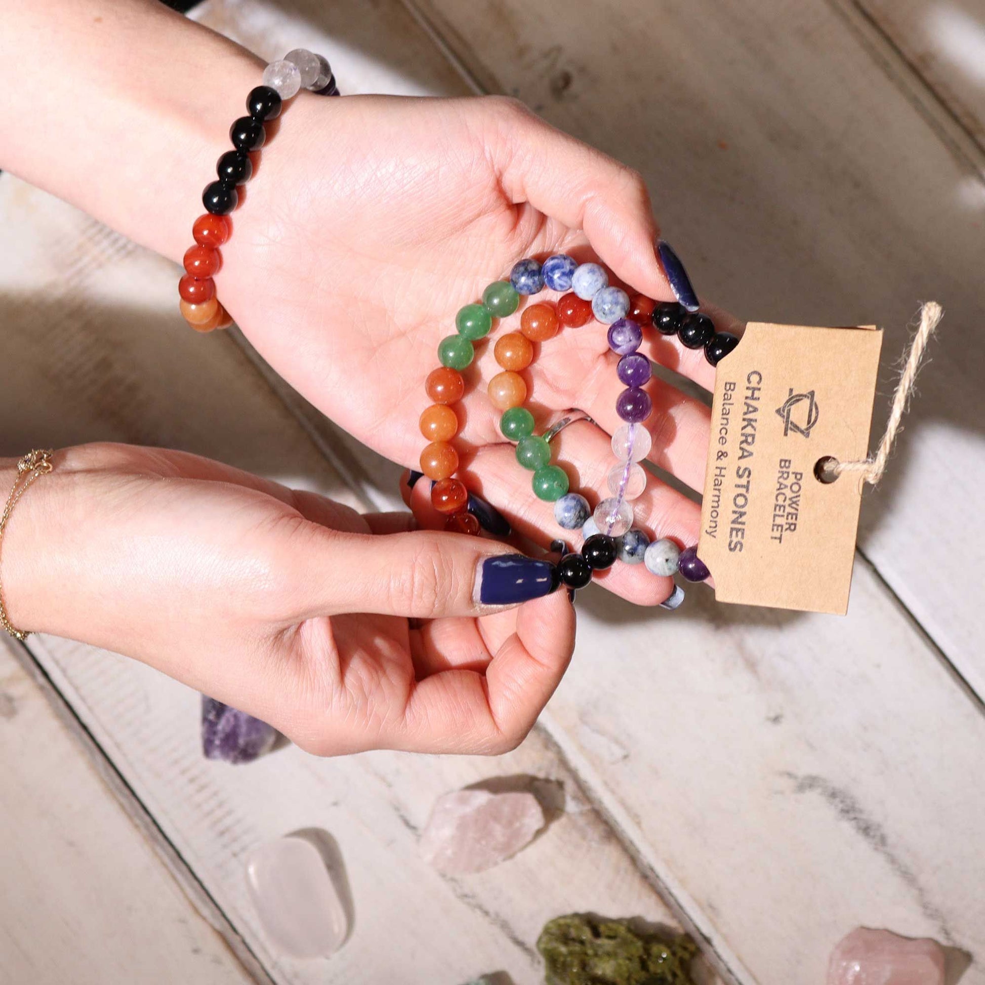 Power Bracelet – Chakra Stones pulsera de cuentas con siete gemas naturales multicolor, hecha a mano, en manos con etiqueta de producto