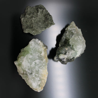 Alt-Tag: Prehnit-Mineralproben – Ca. 100 Stück, drei rohe, gelbgrüne Prehnit-Proben auf dunklem Hintergrund