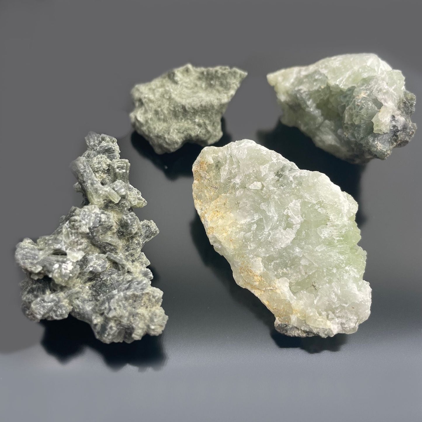 Alt-Tag: Prehnit-Mineralproben – ca. 100 Stück, grün-gelbe Prehnit-Rohsteine auf dunklem Hintergrund, Exemplare aus Marokko