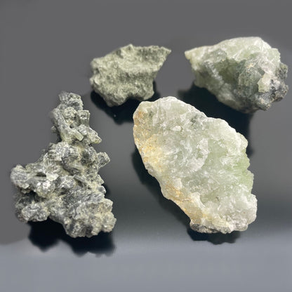 Alt-Tag: Prehnit-Mineralproben – ca. 100 Stück, grün-gelbe Prehnit-Rohsteine auf dunklem Hintergrund, Exemplare aus Marokko