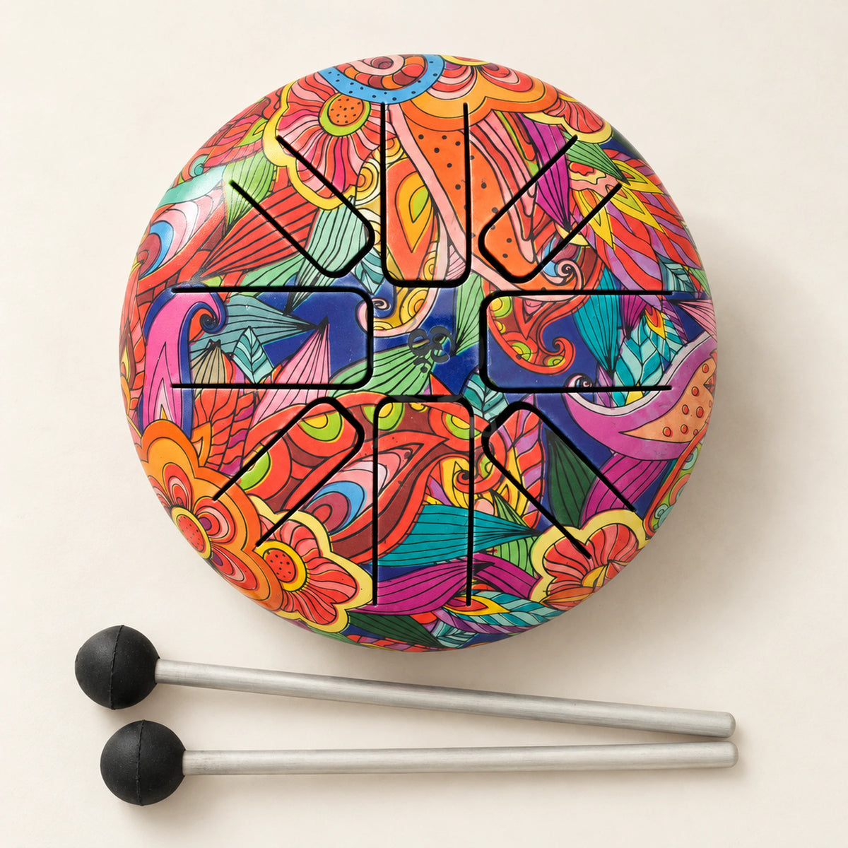 Overhead view of the Happy Drum with colourful floral and leaf artwork and two mallets on an ivory surface.