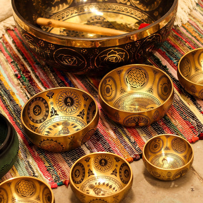 Alt Tag: Tibetanska klangskålar i ren mässing – set om 4 – 3,85 kg, skålar graverade med spirituella symboler och klubba på vävd matta