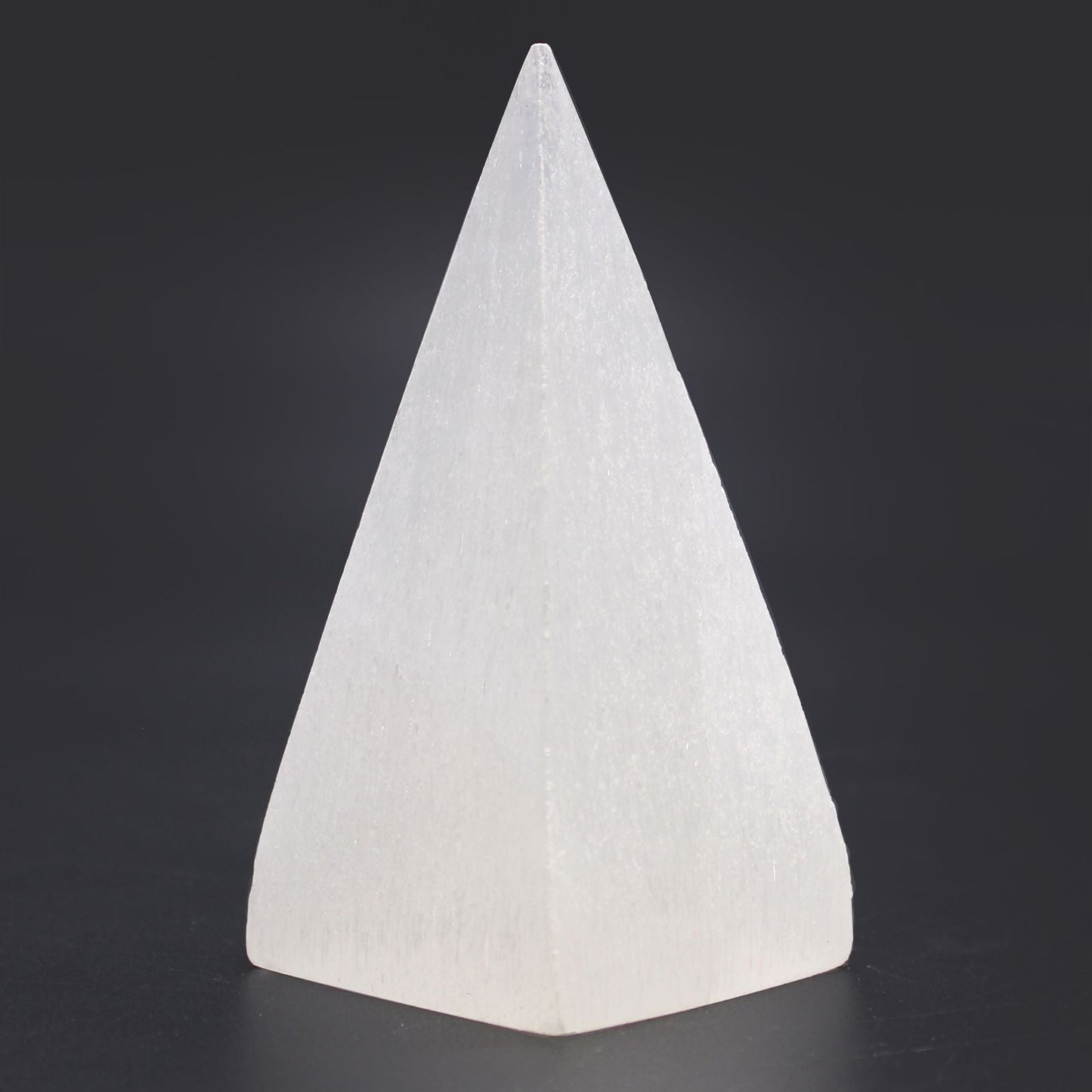 Radiant Selenite Pyramid – 10 CM crystal pyramid, white polished selenite stone decor piece on dark background