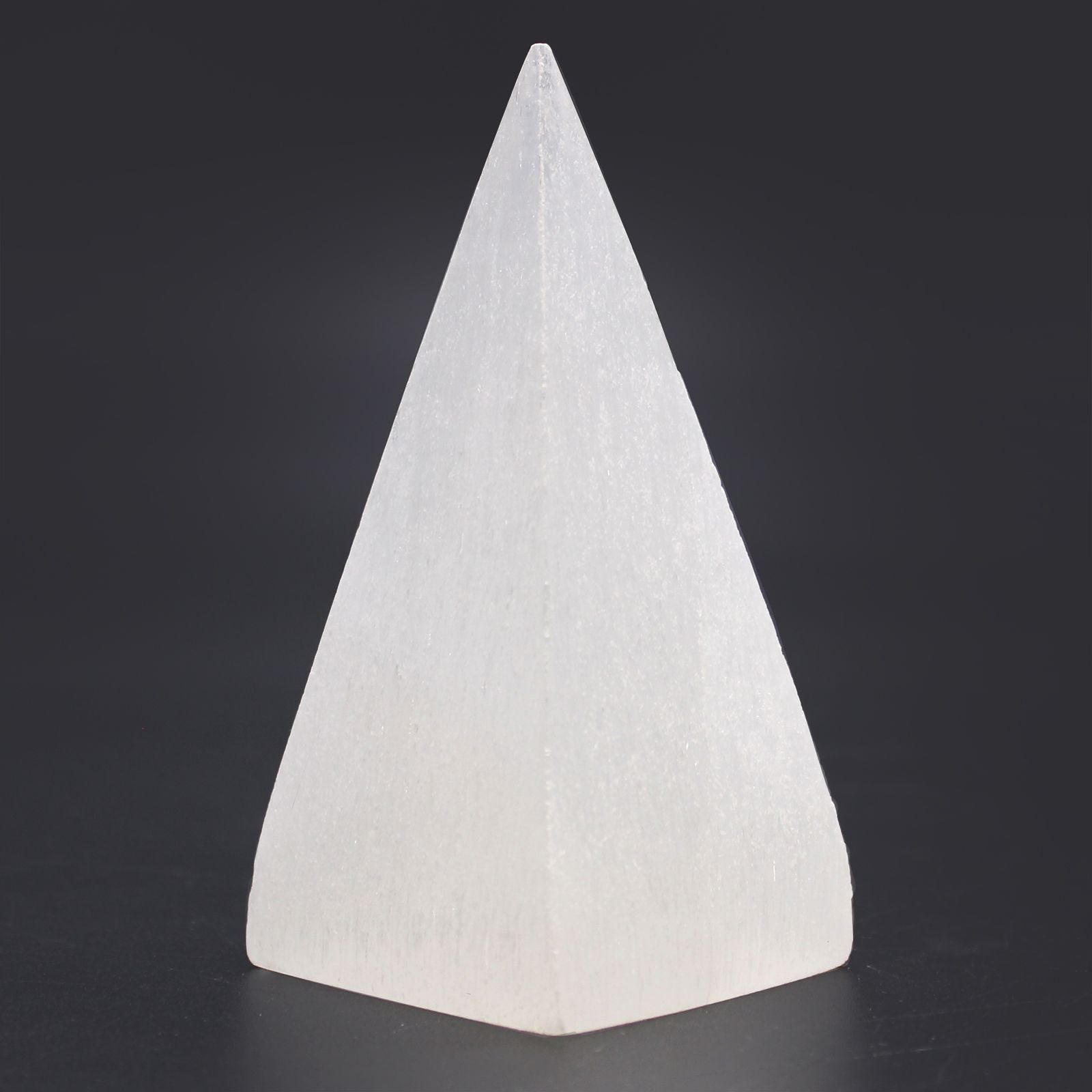 Radiant Selenite Pyramid – 10 CM crystal pyramid, white polished selenite stone decor piece on dark background