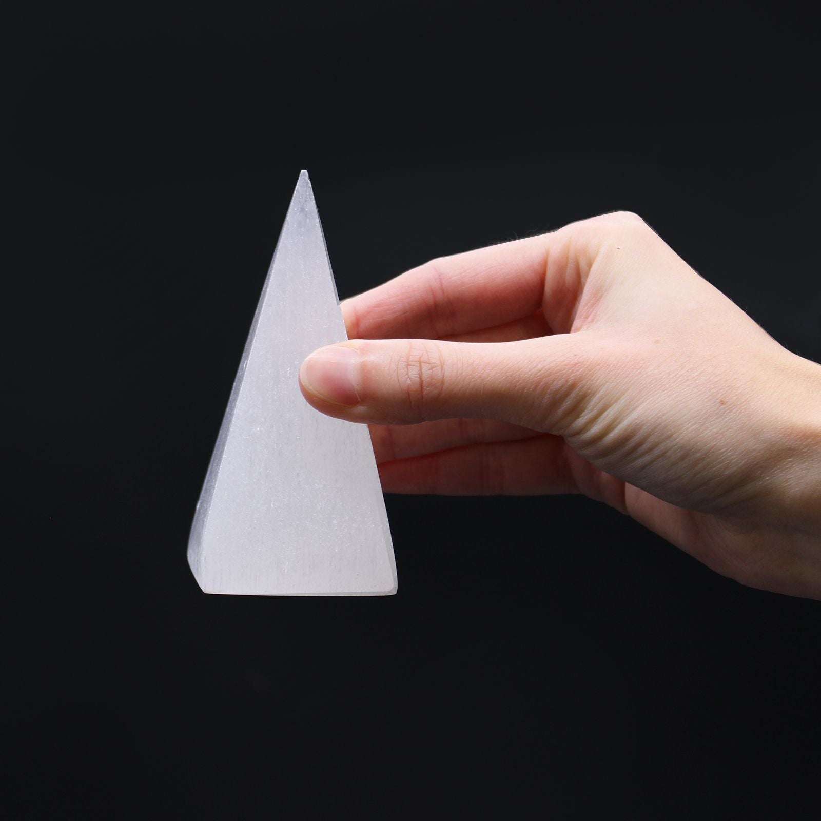 Alt Tag: Radiant Selenite Pyramid – 10 CM held in hand, white selenite crystal pyramid on black background