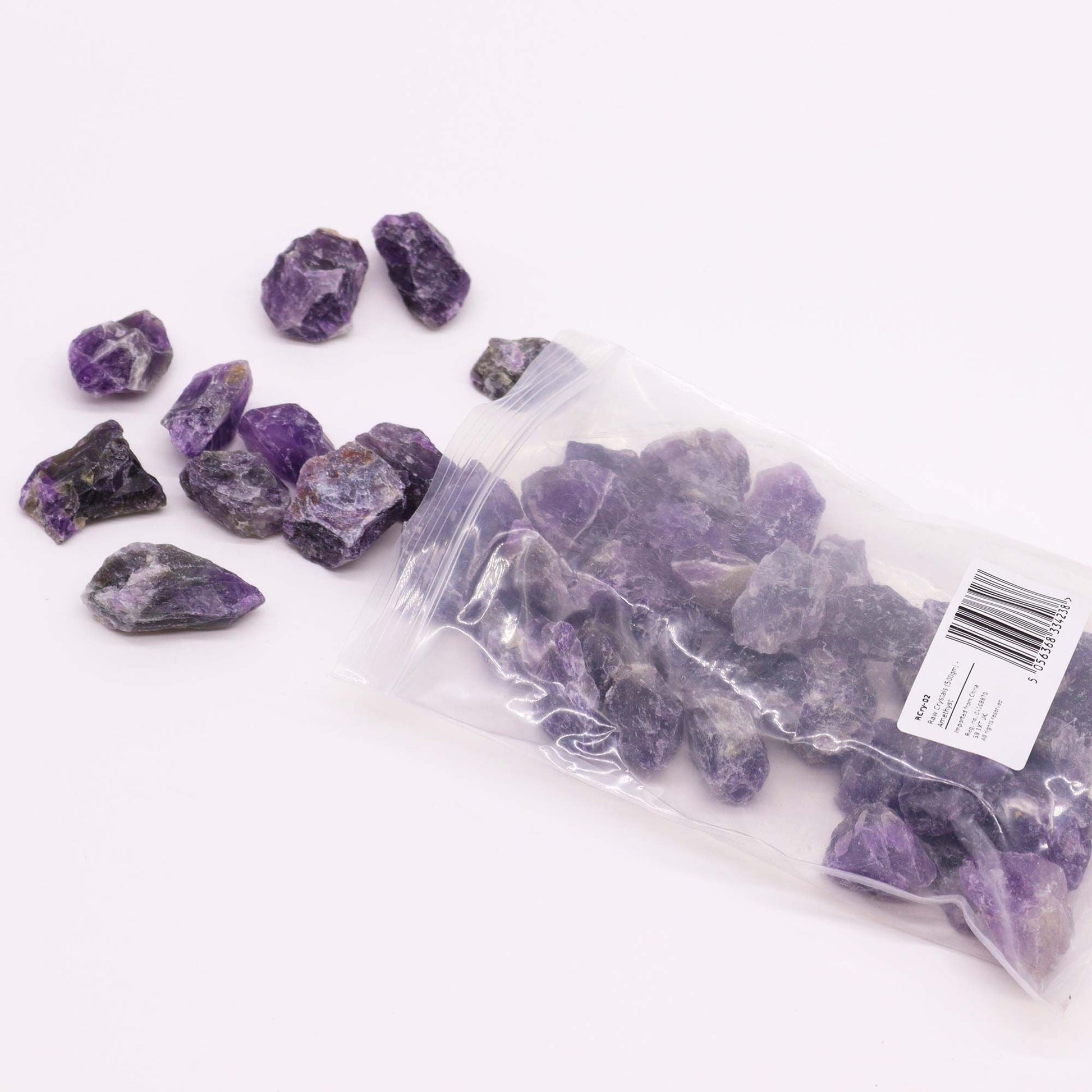 Alt Tag: Amethyst Gemstone – Raw Crystals 500GM en bolsa transparente, piedras amatista moradas sin pulir sobre fondo blanco