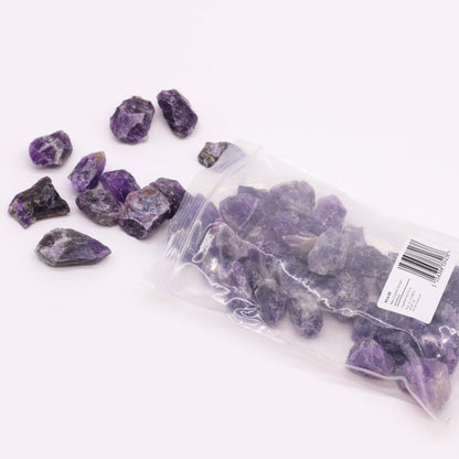 Alt Tag: Amethyst Gemstone – Raw Crystals 500GM en bolsa transparente, piedras amatista moradas sin pulir sobre fondo blanco