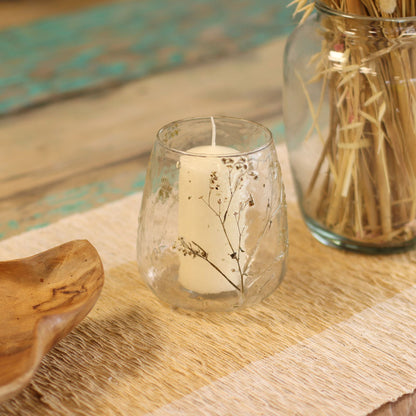 Portavelas de vidrio reciclado – Margarita 12x11CM con flores secas incrustadas, portavelas decorativo con vela blanca sobre mesa de madera