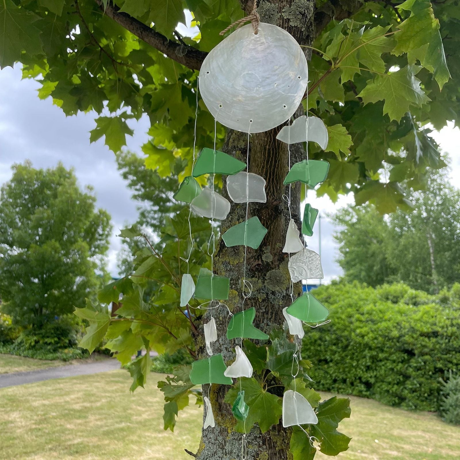 Alt Tag: Vindspel i återvunnet glas – grön & vit 60 CM hängande i träd, delar av återvunnet grönt och vitt glas med drivved