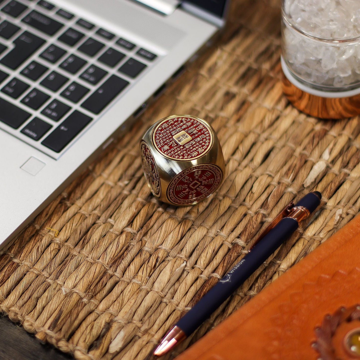 Alt Tag: Red Brass Prosperity Spinner – 4x4 CM sobre escritorio junto a laptop y bolígrafo, acabado en latón y rojo con símbolos