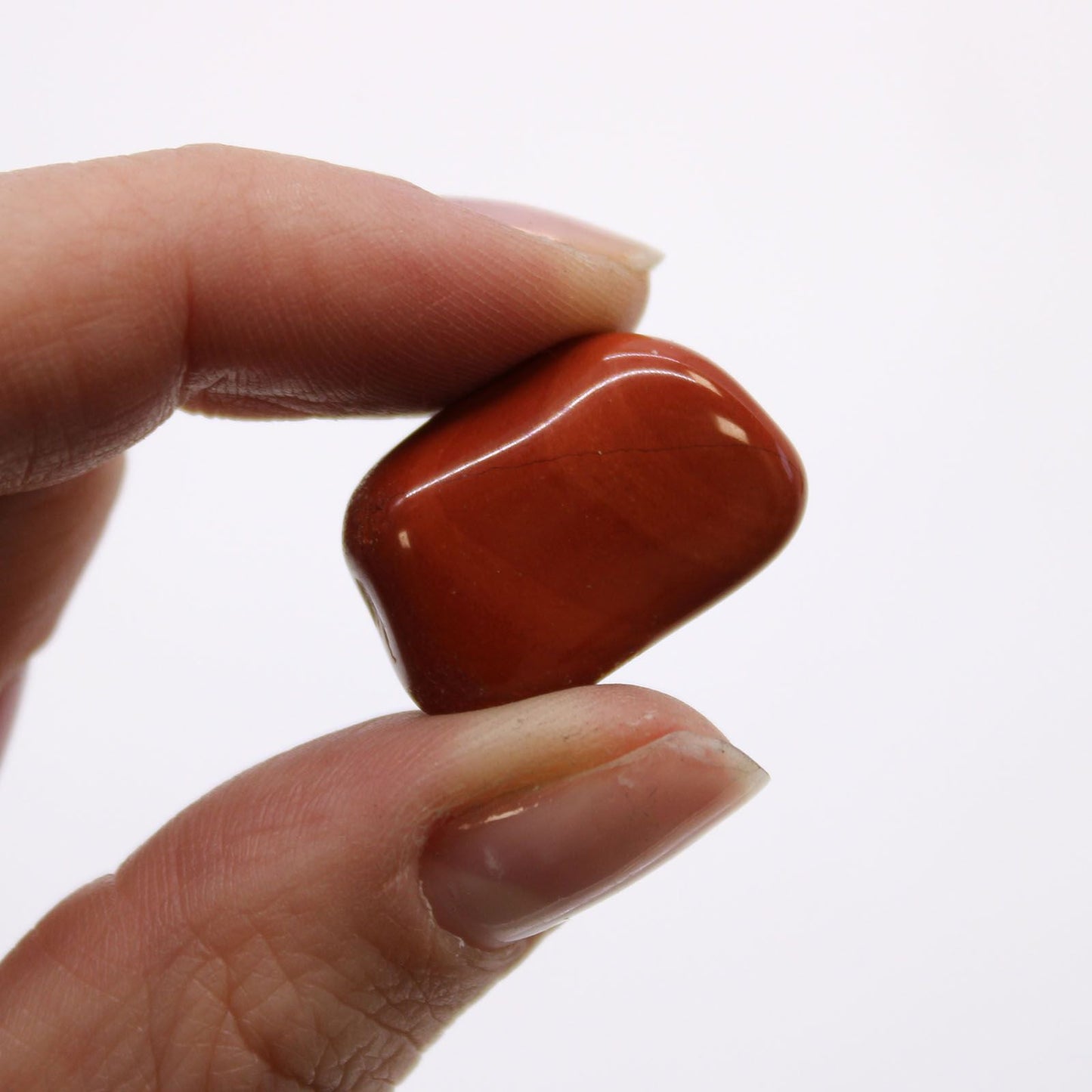 Alt Tag: Red Jasper Gemstone Tumble Stones – Bag of 24, close-up of a polished red jasper tumble stone held between fingers