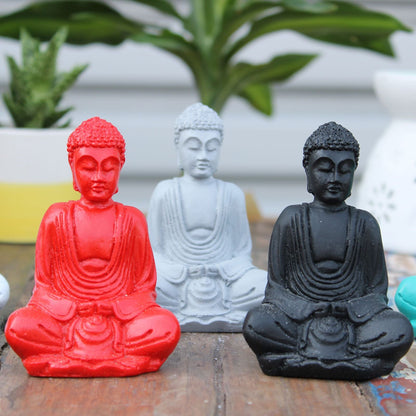 Alt Tag: Mini Buda de resina pintado a mano – figuritas de mini Buda en colores surtidos (rojo, blanco y negro) de resina, sentado sobre una superficie de madera