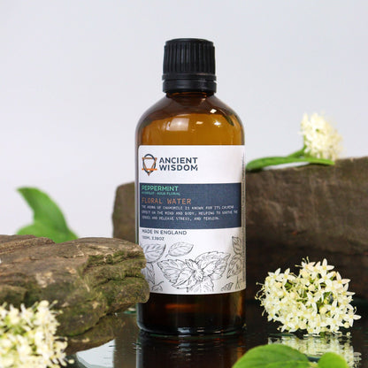 Revitalizing Peppermint Hydrolat – 100ML bottle of peppermint floral water (Mentha Piperita) with label, on stones with white flowers