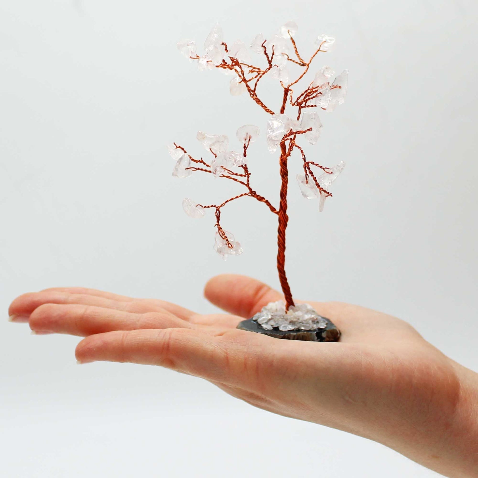 Alt Tag: Rock Quartz Gemstone Tree – 35 Stones on Agate Base on hand, copper wire branches with clear quartz stones, black agate base