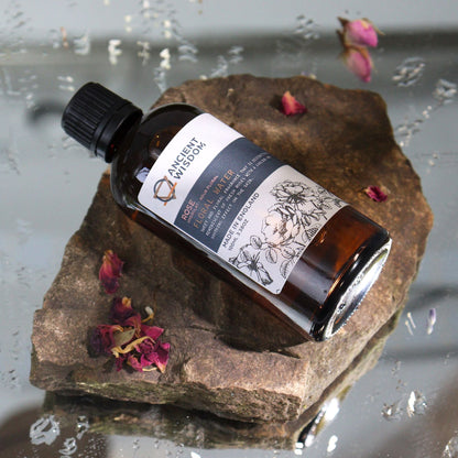 Alt Tag: Rosa Damascena Hydrolat Floral Water – 100ML bottle on stone with rose petals, premium floral water