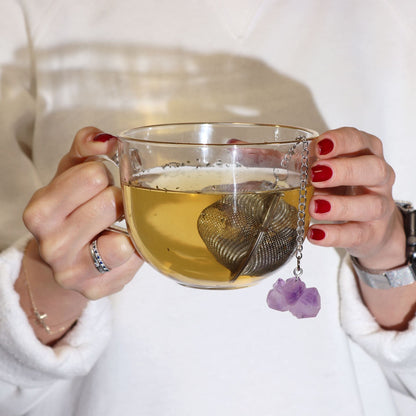 Alt Tag: Rose Quartz Crystal Tea Strainer – 7.5x5 CM colador de té con cadena y cristal rosa colgante en taza de vidrio con infusión