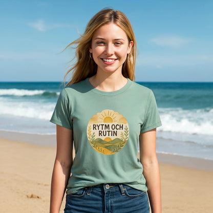 Rytm Rutin Bomulls Premium Unisex T-Shirt en color verde salvia con estampado “RYTM OCH RUTIN”, modelo en la playa