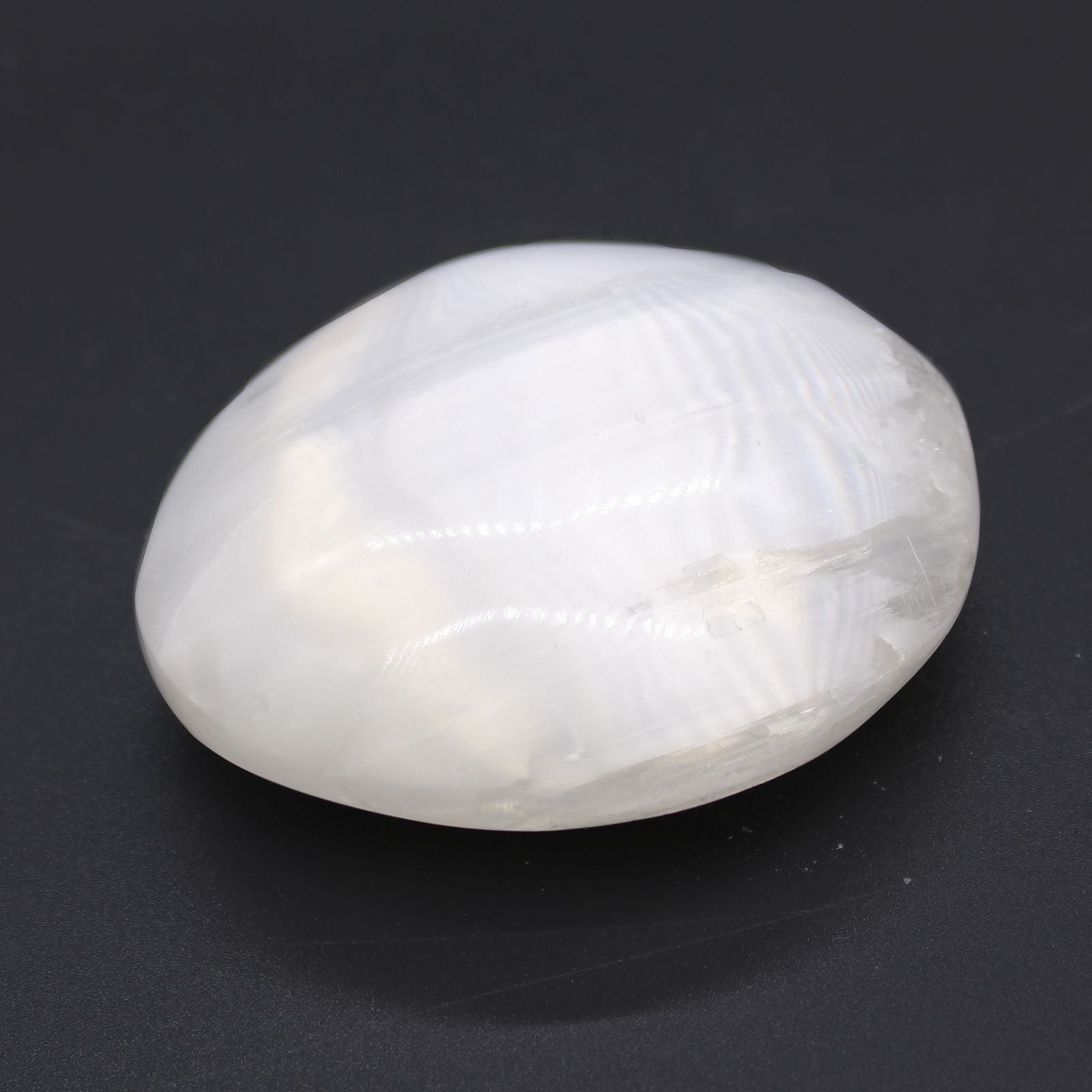 Alt Tag: Selenite Palm Stone – 5-7 CM white polished selenite palm stone with silky sheen on dark background