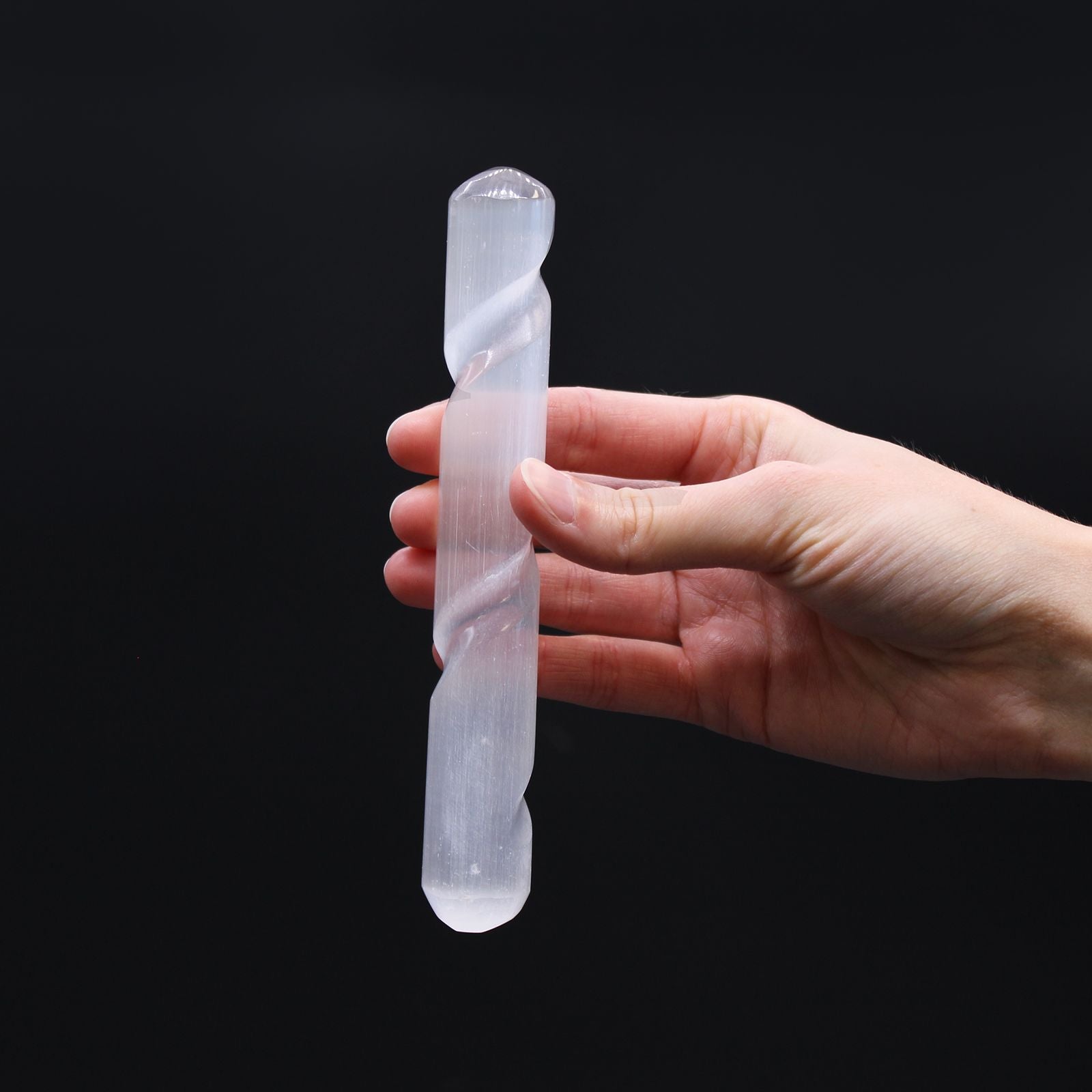 Selenite Spiral Wand – 16 CM Round Ends held in hand, white selenite crystal spiral wand with round ends on black background