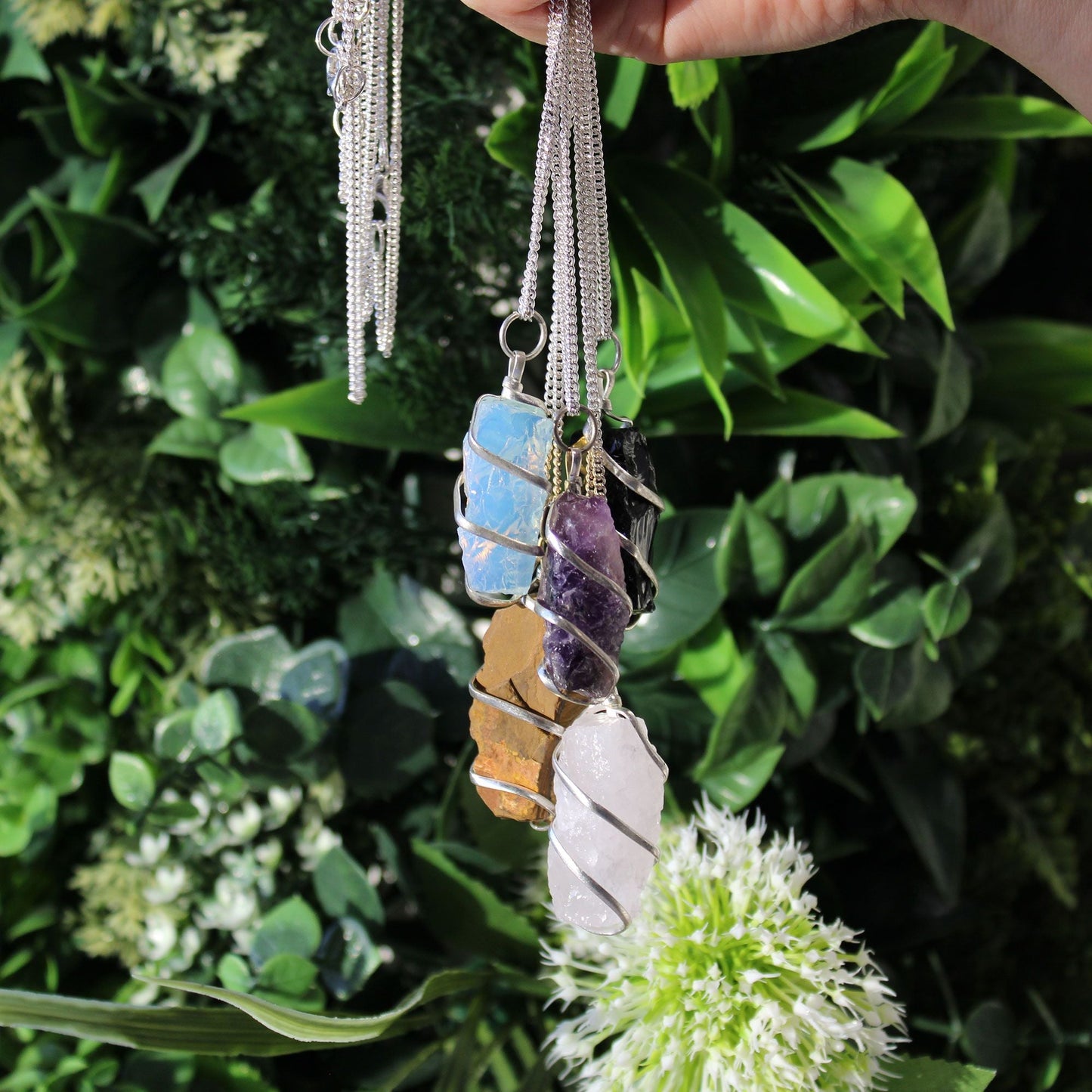 Alt Tag: Silver-Plated Cascade Necklace – Rough Opalite silver-plated necklace with rough opalite pendant on chain, photographed against green leaves
