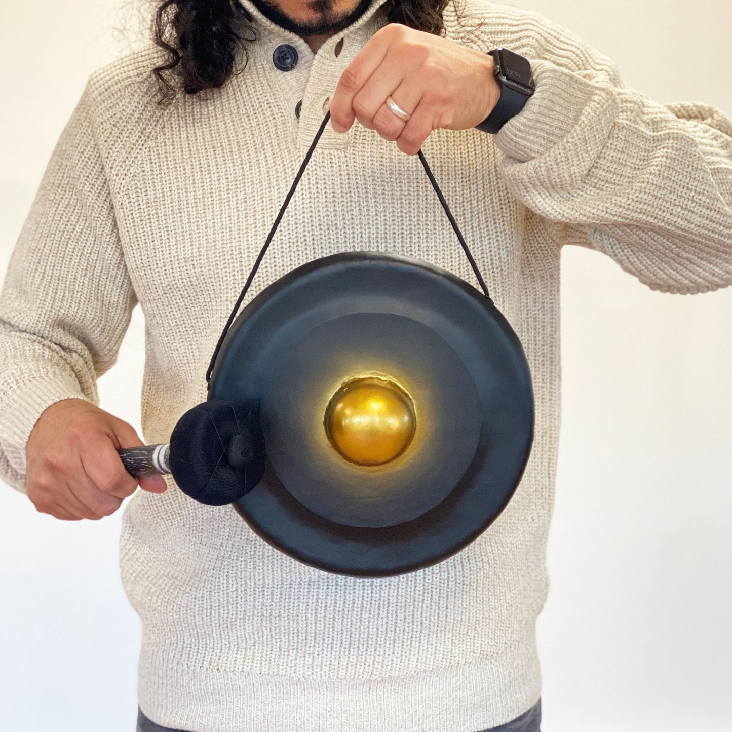 Small Harmonizing Gong in Stand – 25 CM – Black held by person with mallet, black gong with gold center and hanging cord