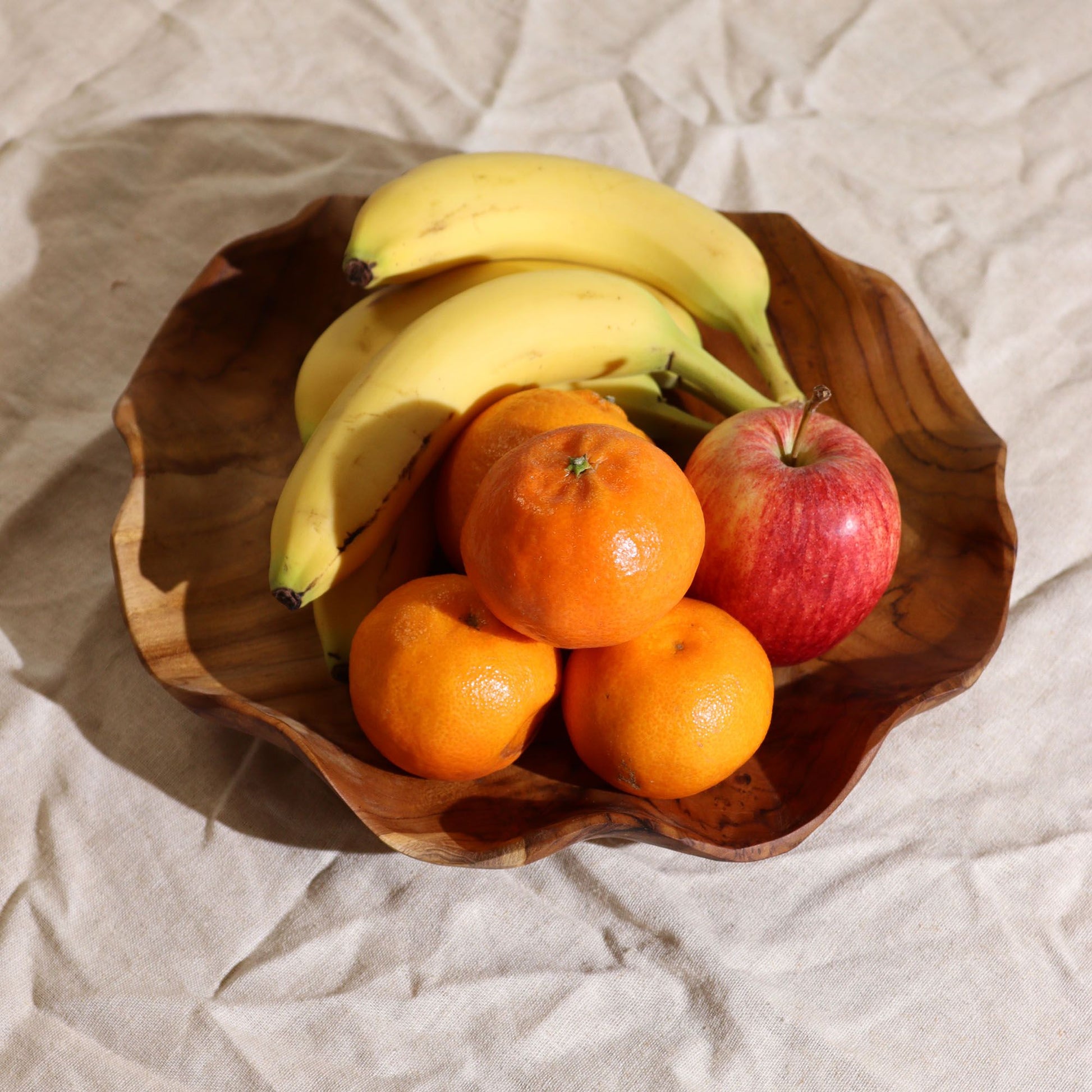 Alt Tag: Smooth Round Teakwood Fruit Bowl – 28 × 5.5 CM with bananas, oranges and apple on a dining table