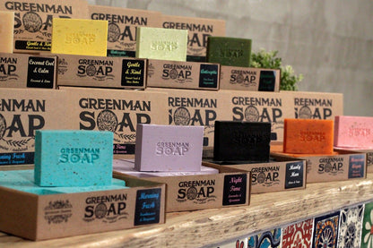 Sodium Palmate Greenman Soap – 100G Gentle & Kind assorted Greenman Soap bars in colorful packaging on wooden display shelf