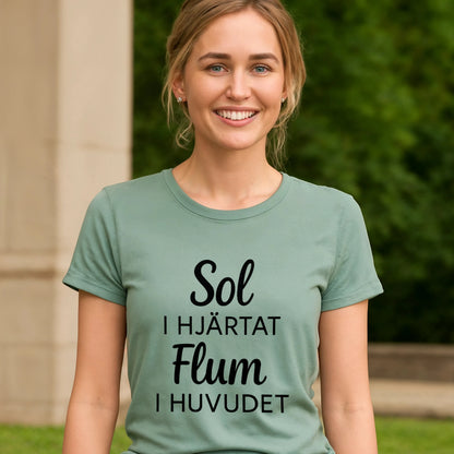 Alt Tag: Sol I Hjärtat Flum I Huvudet 100% Organic Cotton T-Shirt on model, sage green tee with black “Sol I Hjärtat Flum I Huvudet” text