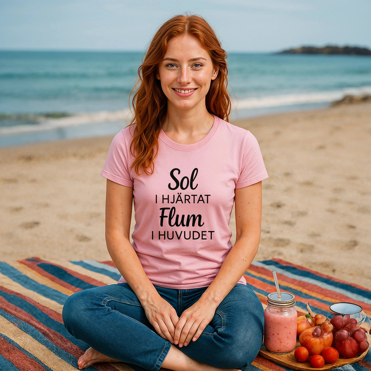 Sol I Hjärtat Flum I Huvudet 100% Organic Cotton T-Shirt worn by woman on beach, pink tee with “Sol I Hjärtat Flum I Huvudet” text