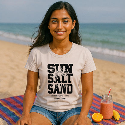 Alt Tag: Model wearing Sol Salt Sand 100% Organic Cotton T-Shirt with “SUN SALT SAND” print, seated on beach blanket by the ocean