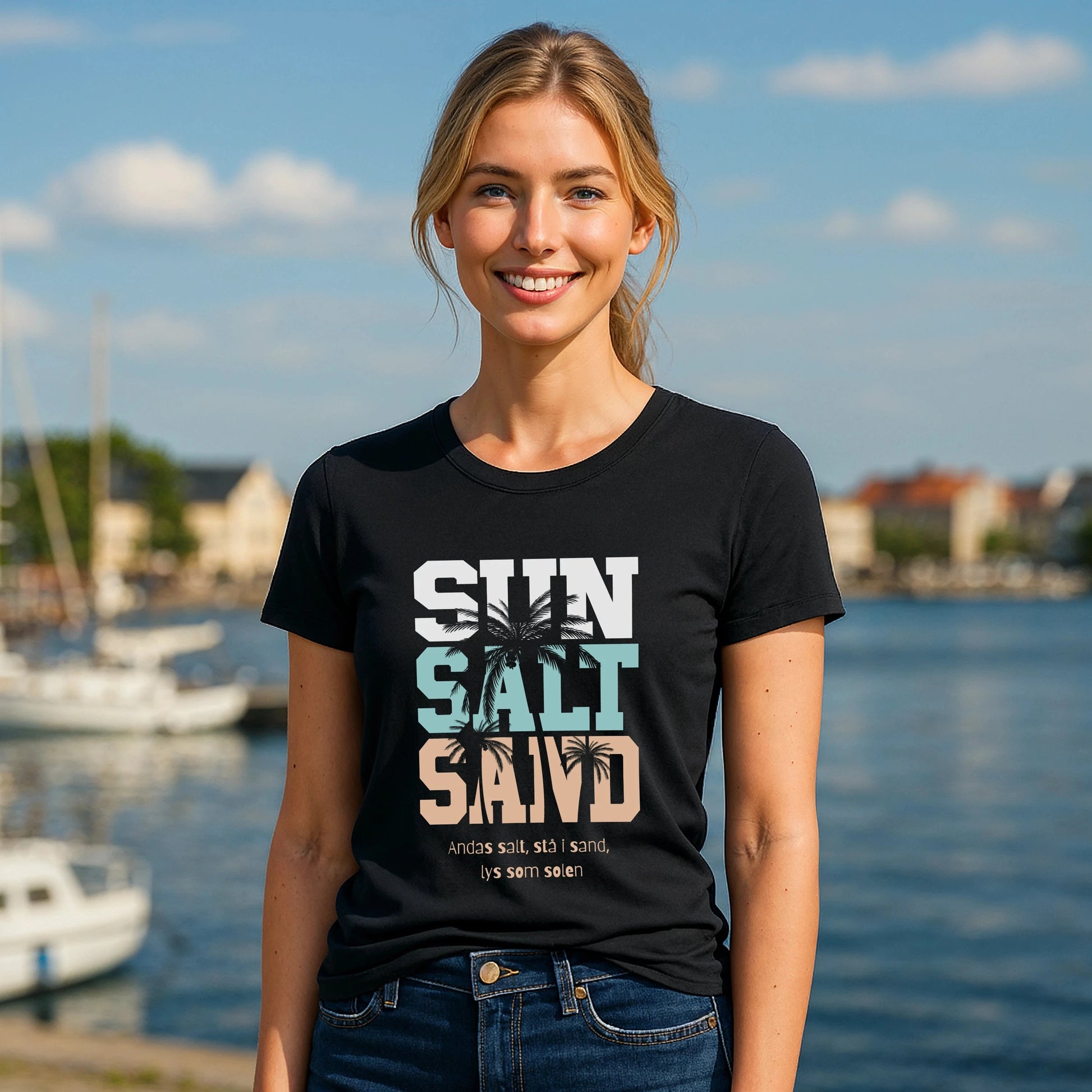 Alt Tag: Model wearing Sol Salt Sand 100% Organic Cotton T-Shirt with "Sun Salt Sand" graphic, black tee by the marina
